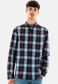 Camicia a maniche lunghe a quadri in nero, blu e rosso, con design a bottoni e un piccolo logo sul lato sinistro del petto. Tessuto dalla morbida texture.