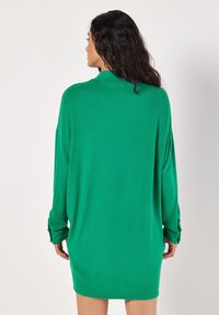 Zelené oversized dlouhé šaty s dlouhým rukávem a kulatým výstřihem, se zapínáním na knoflíky na manžetách. Měkká, strukturální tkanina s hladkým povrchem.