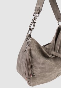 Sac à main gris doux perforé avec une large bandoulière, des ferrures argentées et un pompon suspendu à un anneau métallique.