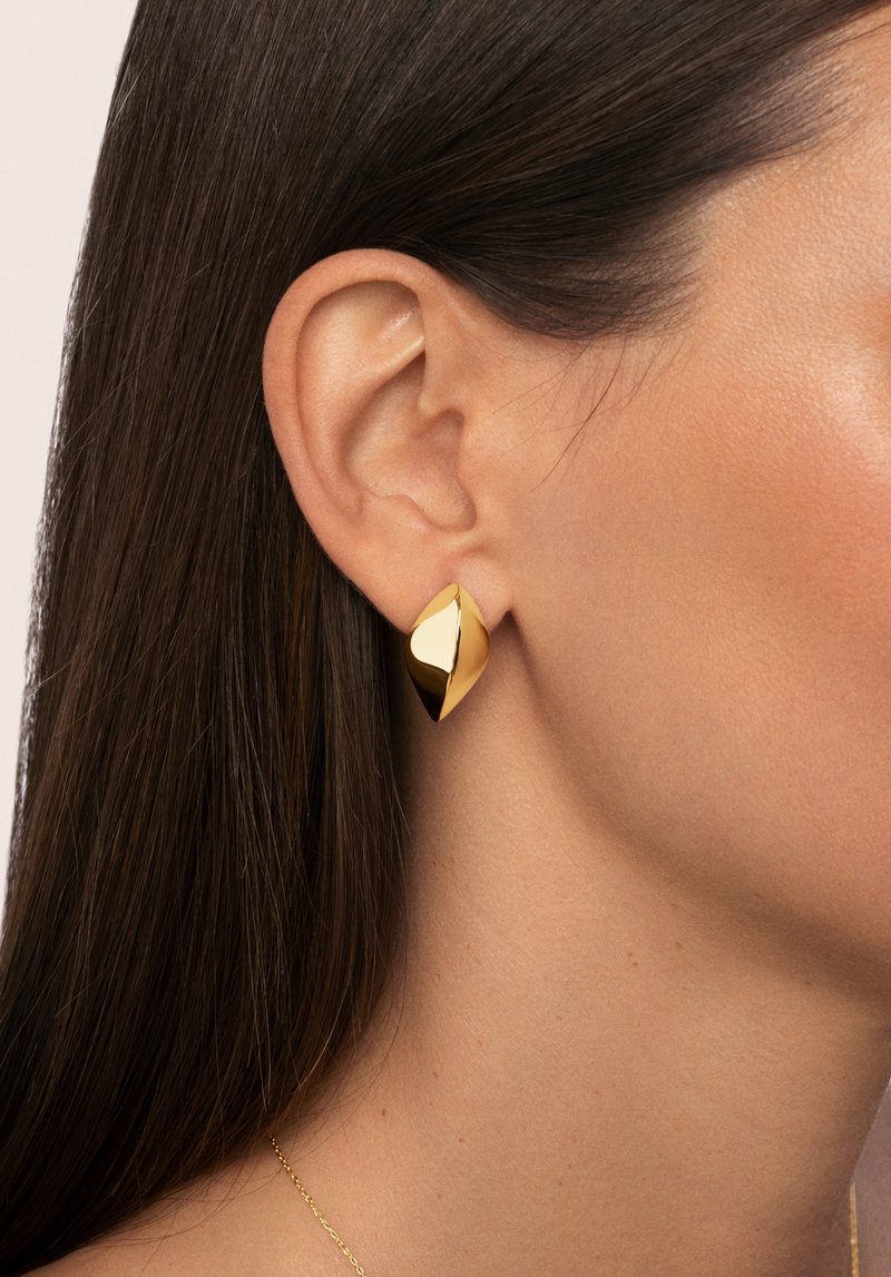Pendientes de oro en forma de hoja, con una superficie pulida y reflectante, con curvas suaves y un diseño elegante.