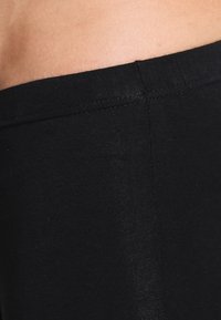 Leggings neri in un tessuto liscio e elastico. Presentano un waistband alto con una vestibilità aderente e cuciture sottili lungo le cuciture.