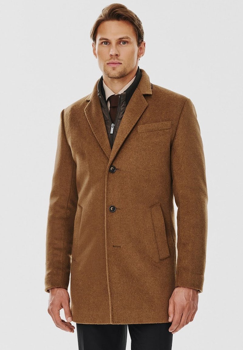 Brązowy płaszcz z mieszanki wełny, z klapami, dwiema przednimi kieszeniami i zapięciem na jeden guzik. Teksturowa powierzchnia i dopasowany krój.