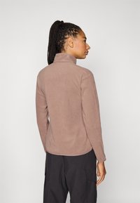 Chaqueta de forro polar en topo con cuello alto y mangas largas. Textura suave, diseño ajustado y dobladillo curvado para mayor comodidad.