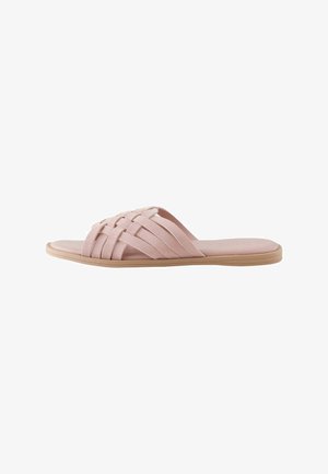 Litessä sandaalissa on kudotut vaaleanpunaiset mokkanauhat ja vaalea ruskean sävyinen pohja, esitetty sivulta valkoisella taustalla.