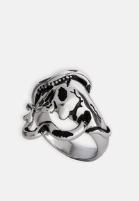 Zilveren ring met een intricaat ontwerp, voorzien van een gesculptureerd gezicht, een gladde textuur en contrasterende zwarte details.