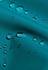 Türkiser Stoff mit strukturierten Oberflächen, der Wassertropfen zeigt und seine wasserabweisenden Eigenschaften sowie die glatte Oberfläche unterstreicht.