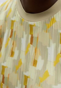 Plisovaná tkanina s pastelovou barevnou paletou žluté, béžové a světle zelené barvy s abstraktními tvary; měkká textura; pevný béžový výstřih.