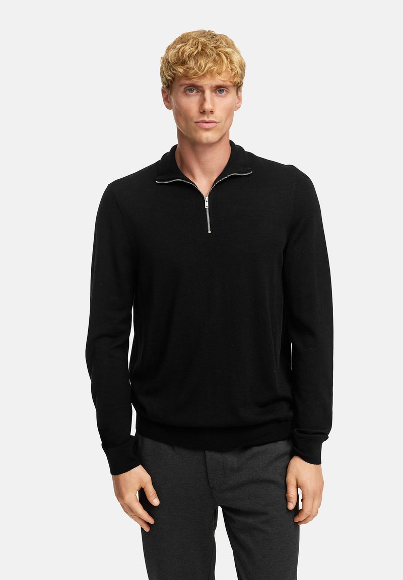 Zwarte pullover trui met een kwart rits, gebreide structuur, lange mouwen en geribde manchetten en onderkant. Draag over donkergrijze broek.