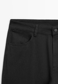 Black denim pants featuring a classic five-pocket design, a button closure, and visible stitching details along the waistband and pockets.