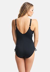 Maillot de bain noir une pièce avec bretelles ajustables, dos nu et détails froncés sur les côtés. Texture lisse et silhouette moulante.