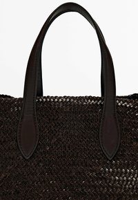 Geweven bruine tote bag met gladde leren handvatten. Het gestructureerde lichaam heeft een kruispatroon, aangevuld met donkere leren accenten.