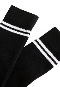Calzini neri in cotone con trama a coste e due strisce bianche sulla parte superiore. Presentano un design atletico classico.