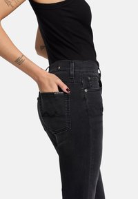 Schwarze Jeans aus Denim mit einem taillierten Design, ausgestattet mit einer Akzenttasche auf der Rückseite, strukturiertem Stoff und einem mittelhohen Bund.