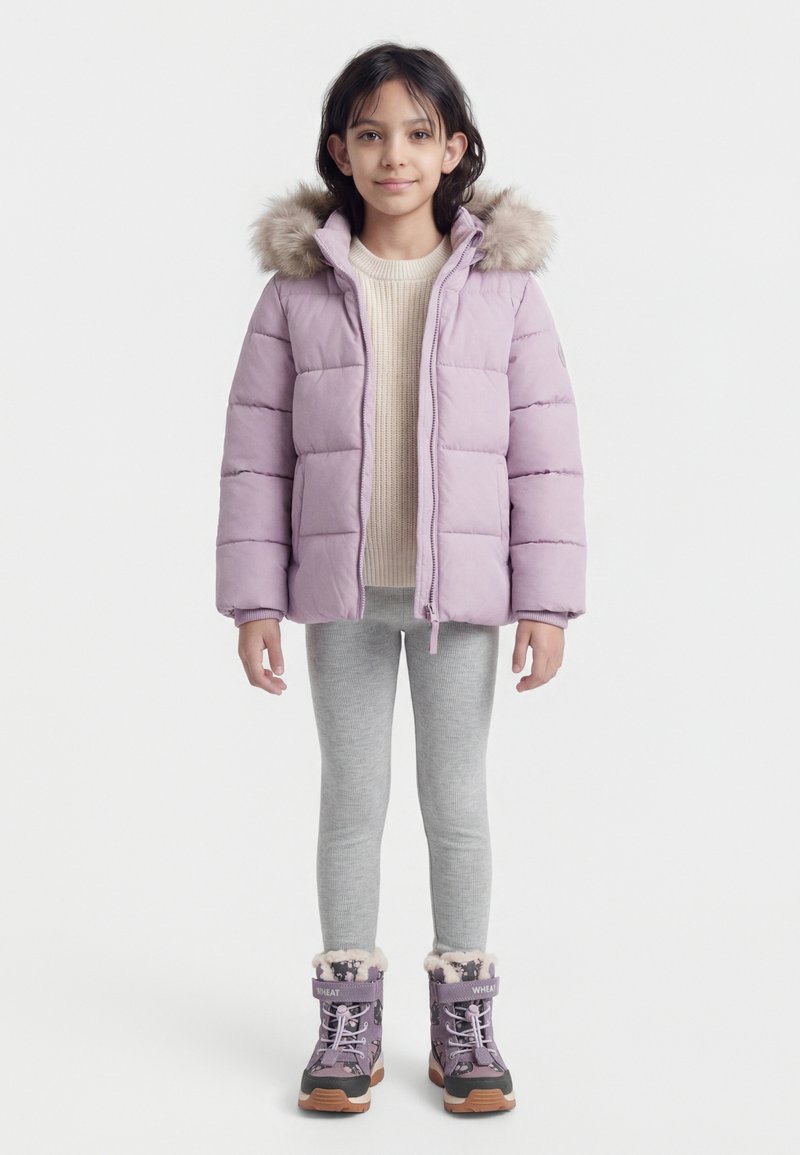 Jeune fille portant une doudoune violette claire avec une capuche en fourrure, un pull crème, des leggings gris et des bottes d'hiver violettes.