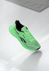 Neon zaļi skriešanas apavi ar melniem akcentiem, elpojoša acs aug�šdaļa, mīksts zole un atstarojoši elementi, ar mīkstinātu apkaklīti un šņorēm.