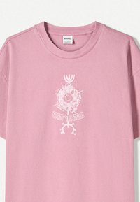 Pink cotton t-shirt featuring a white graphic design with the text "SILENT STRENGTH" and decorative elements below the neckline.