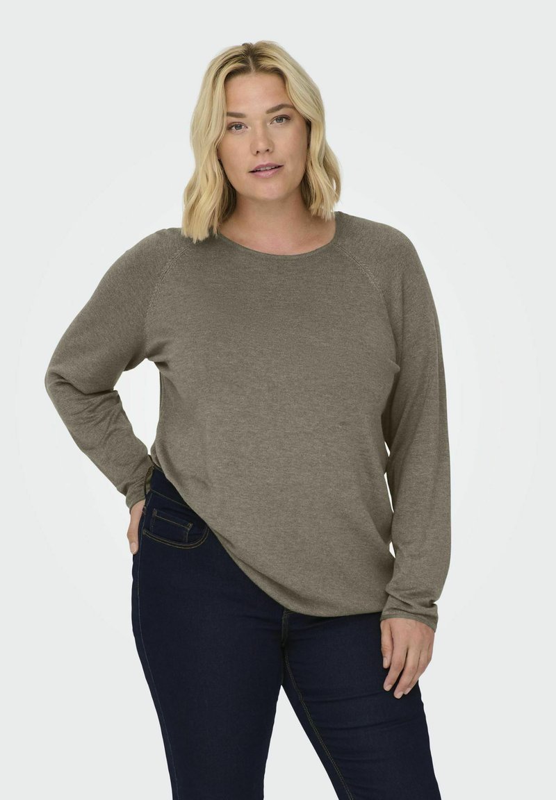 Chemise taupe à manches longues avec un col rond et des manches raglan, assortie à un jean bleu foncé. Texture douce, coupe décontractée, design minimal.