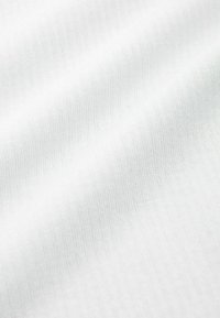 Valkoinen kangas, jossa on hieno ribbitekstuuri, joka näyttää hienovaraisia vaalean sävyjä ja sileän pinnan.