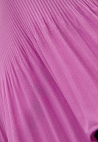 Gros plan sur un tissu rose avec de fines plis verticaux et une surface légèrement texturée.