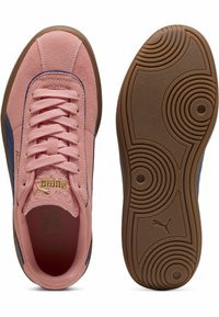 Zapatillas de ante rosa con acentos azules, cordones planos y detalle de marca en dorado. Suela de goma marrón texturizada con patrón circular.