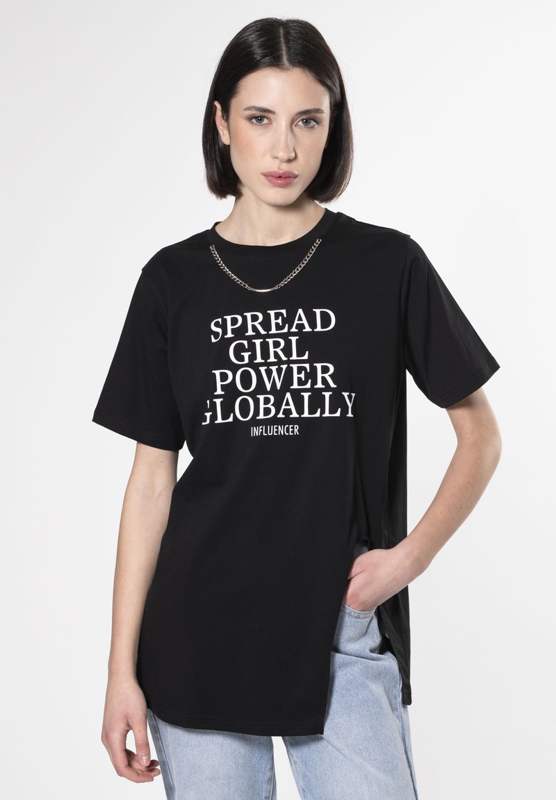 Camiseta de algodón negra con el texto blanco "PROPAGA EL PODER FEMENINO A NIVEL GLOBAL INFLUENCER", mangas cortas y un accesorio de cadena alrededor del escote.