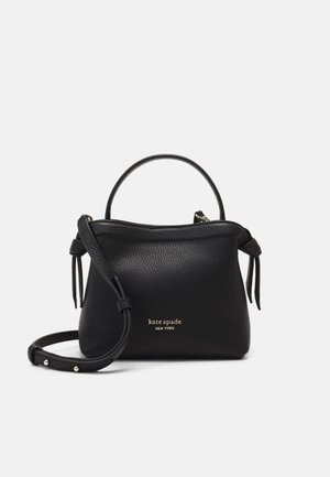 Bolso de mano negro de cuero Kate Spade con asa corta, correa de hombro ajustable y logotipo de marca dorado en el centro delantero.