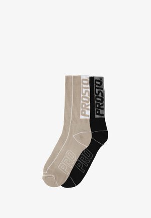 Dwie pary prążkowanych skarpet w kolorze beżowym i czarnym, z kontrastującym napisem "PROSTO" w białym i szarym kolorze na ściągaczach. Wykonane z bawełny.