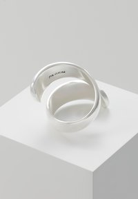 Silver ring with a flowing design, featuring smooth, polished surfaces and a spiral shape. Marked with "Pilgrim" on the inner band.