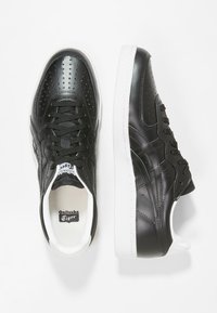 Sneakers in pelle nera con dettagli perforati, suola in gomma bianca e lacci neri. Presentano il marchio Onitsuka Tiger sulla linguetta.