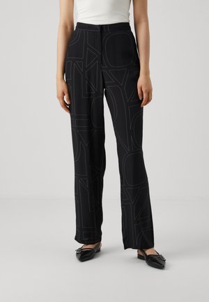 Black trousers with a relaxed fit, featuring a pattern of large, bold letters in contrasting black stitching. Smooth, lightweight fabric.