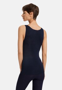 Námořnický tílko s kulatým výstřihem a úzkým střihem. Vyrobeno z hladkého materiálu, bez ozdob či vzorů.