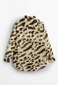 Chemise à boutons imprimée léopard en beige clair et marron foncé, avec un col pointu, des manches longues et une couture centrale au dos.