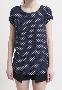 Marineblaue kurzärmlige Bluse mit weißen Punkten, runden Halsausschnitt und entspannter Passform. Strukturierter Stoff mit glatter Oberfläche.