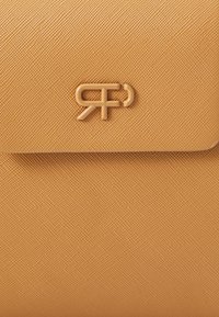 Bolso de mano de textura naranja que presenta un logotipo con acento dorado, con un cierre de solapa suave y un diseño rectangular estructurado.