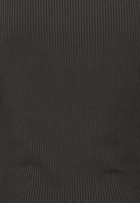 Svart ribbad tyg med ett vertikalt randmönster, med en mjuk textur och en åtsittande design för en figursydd look.