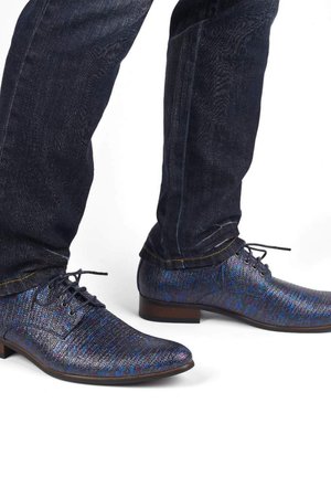 Chaussures habillées à motif bleu foncé avec une surface texturée, bout rond et lacet à l'avant, assorties à un jean en denim foncé.