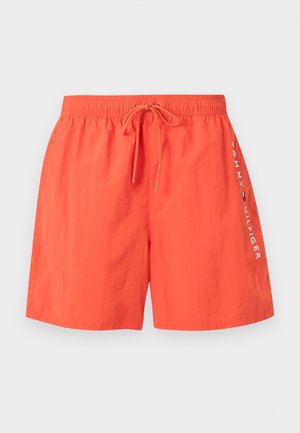 Világos narancssárga fürdőshort elasztikus derékrésszel, zsinórral, oldalzsebekkel és fehér „Tommy Hilfiger” felirattal, valamint logóval a jobb lábon.