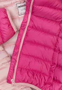 Chaqueta acolchada con exterior rosa brillante, diseño acolchado, forro suave y detalle de cremallera color crema. Etiqueta de talla visible en el interior.