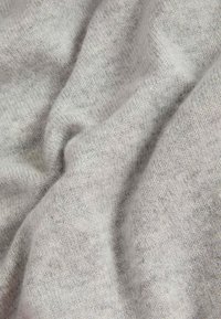 Jasnoszary materiał, o miękkiej strukturze z lekko puszystą powierzchnią. Splot jest gęsty, z subtelnymi wariacjami w kolorze i głębokości.