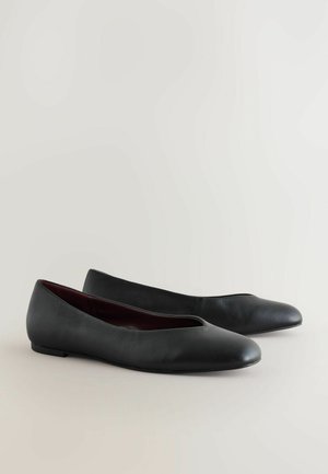 Svart läderballettskor med rund tå och låg klack. Insidan har ett kontrasterande vinrött foder och en sömlös design.