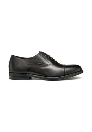 Chaussure de ville en cuir marron foncé avec une finition lisse. Elle présente un laçage et un petit talon, avec des détails de couture discrets sur les côtés.