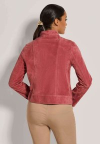 Rote Wildlederjacke mit einem hohen Kragen, figurbetonter Passform und langen Ärmeln. Verfügt über vertikale Nähte und einen Saum, der auf Taillenhöhe endet.