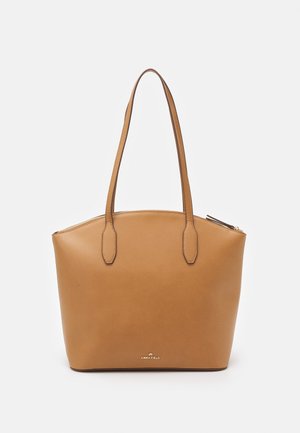 Sac cabas en cuir camel avec texture lisse, deux anses pour les épaules, sommet arrondi, et un logo doré à la base. Fermeture éclair en haut.