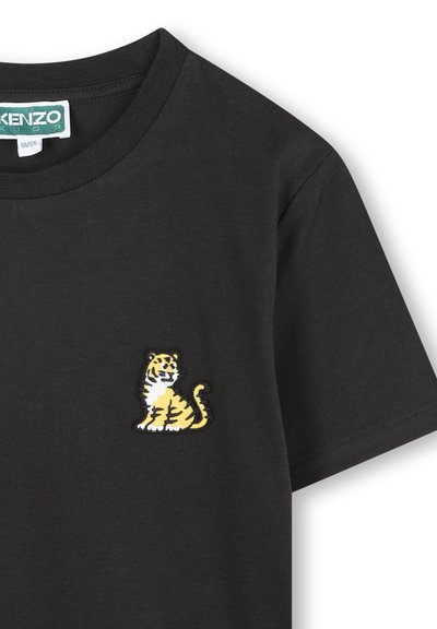 Czarna bawełniana koszulka z haftowanym żółto-białym wzorem tygrysa na lewej piersi. Okrągły dekolt, krótkie rękawy.