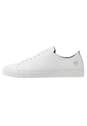 Biały niski skórzany sneaker z białymi sznurowadłami, płaską podeszwą i małym okrągłym logo po stronie pięty.