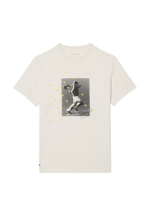 Camiseta color marfil claro con la imagen en blanco y negro de un jugador de tenis en pleno swing, salpicada de puntos amarillos que representan pelotas de tenis.