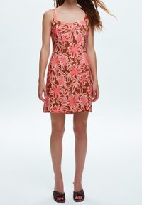 Floral dress featuring a brown base with large pink flowers, thin straps, fitted silhouette, and textured fabric. Classic mini length style.