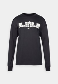 T-shirt a maniche lunghe di colore nero realizzato in misto cotone. Presenta un design grafico bianco e un piccolo logo Nike sul davanti. Vestibilità standard.