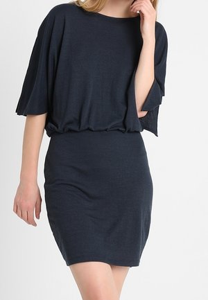 Robe bleu marine foncé en tissu doux, avec un haut ample à manches courtes et une taille froncée, ainsi qu'une jupe moulante.