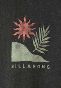 T-shirt nera con una grafica che presenta un sole rosso, una foglia verde e una forma astratta. Testo "BILLABONG" in verde sotto il design. Tessuto in cotone.